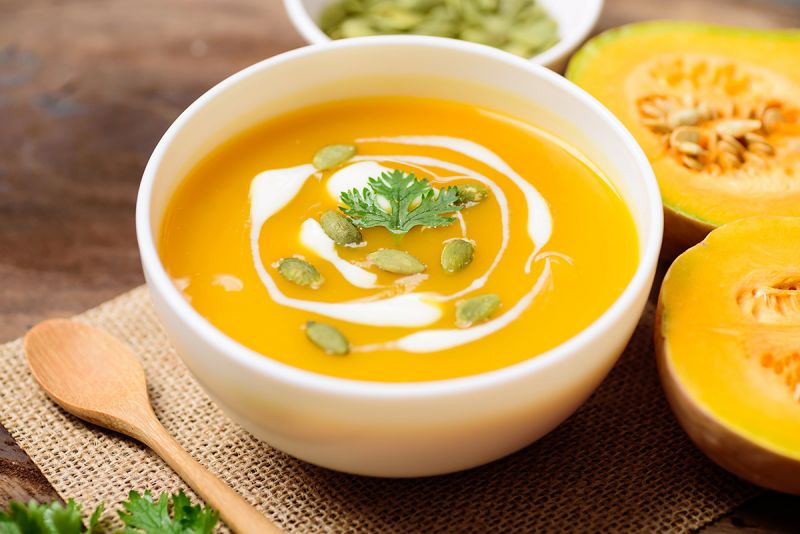 A bowl of squash soup with pumpkin seeds.